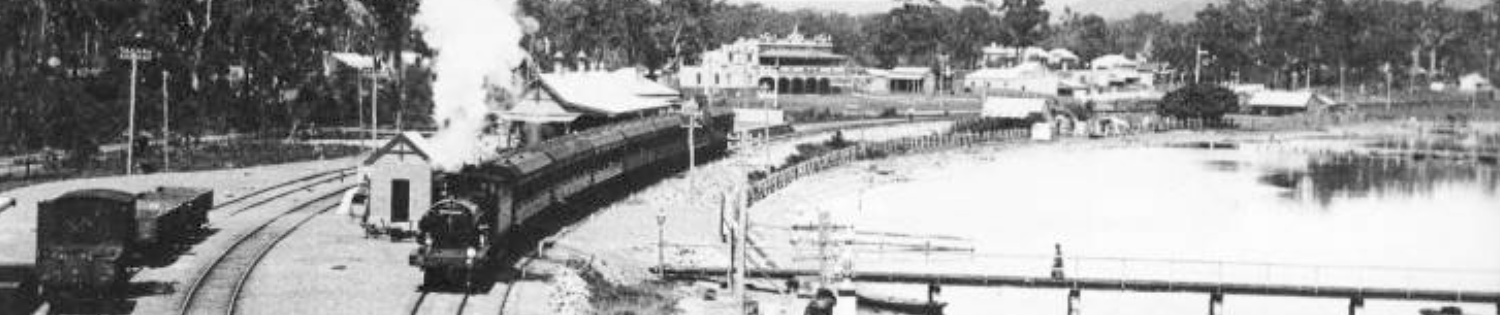 black and white photo of a train by water